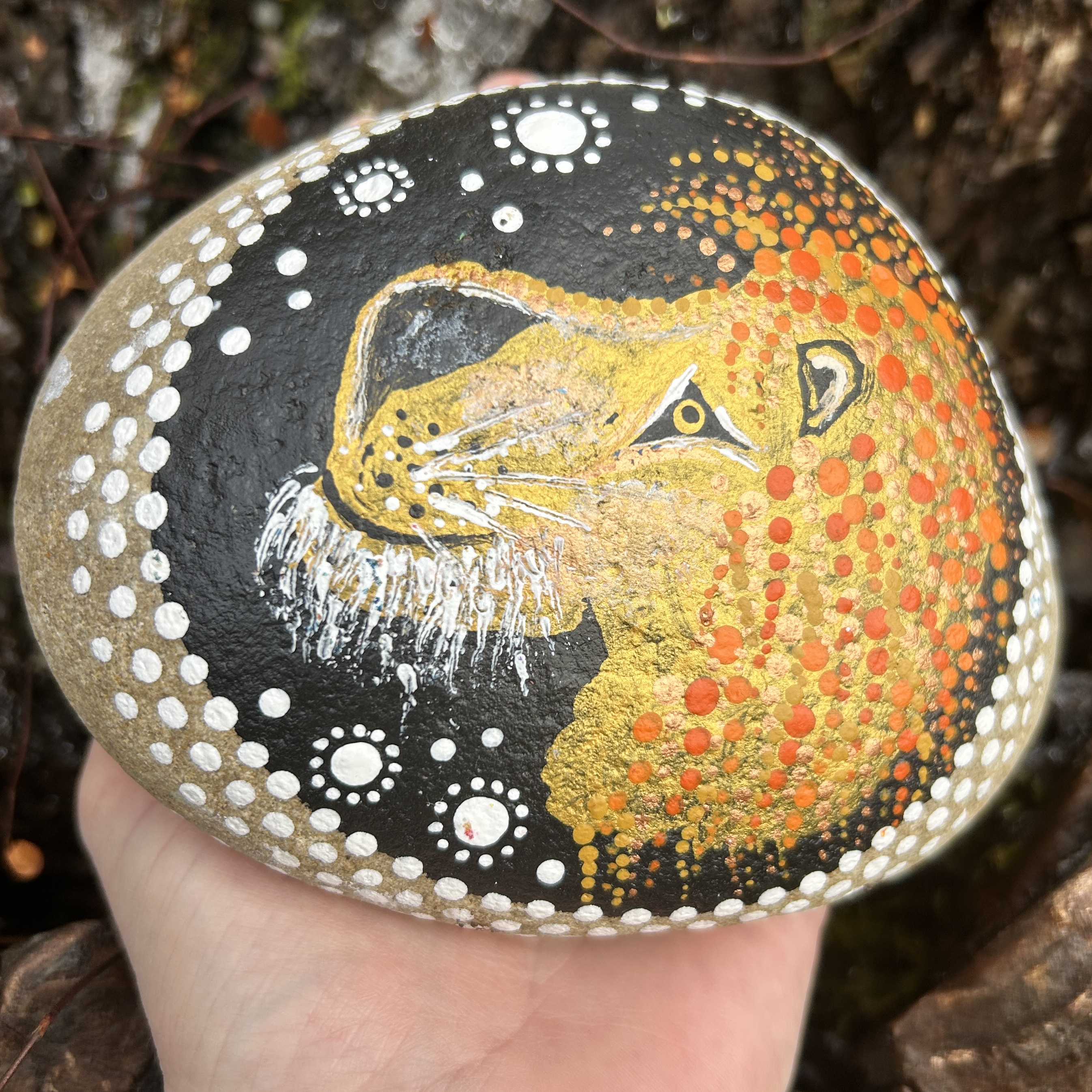 Stein mit Löwenkopf bemalt wird in Hand gehalten