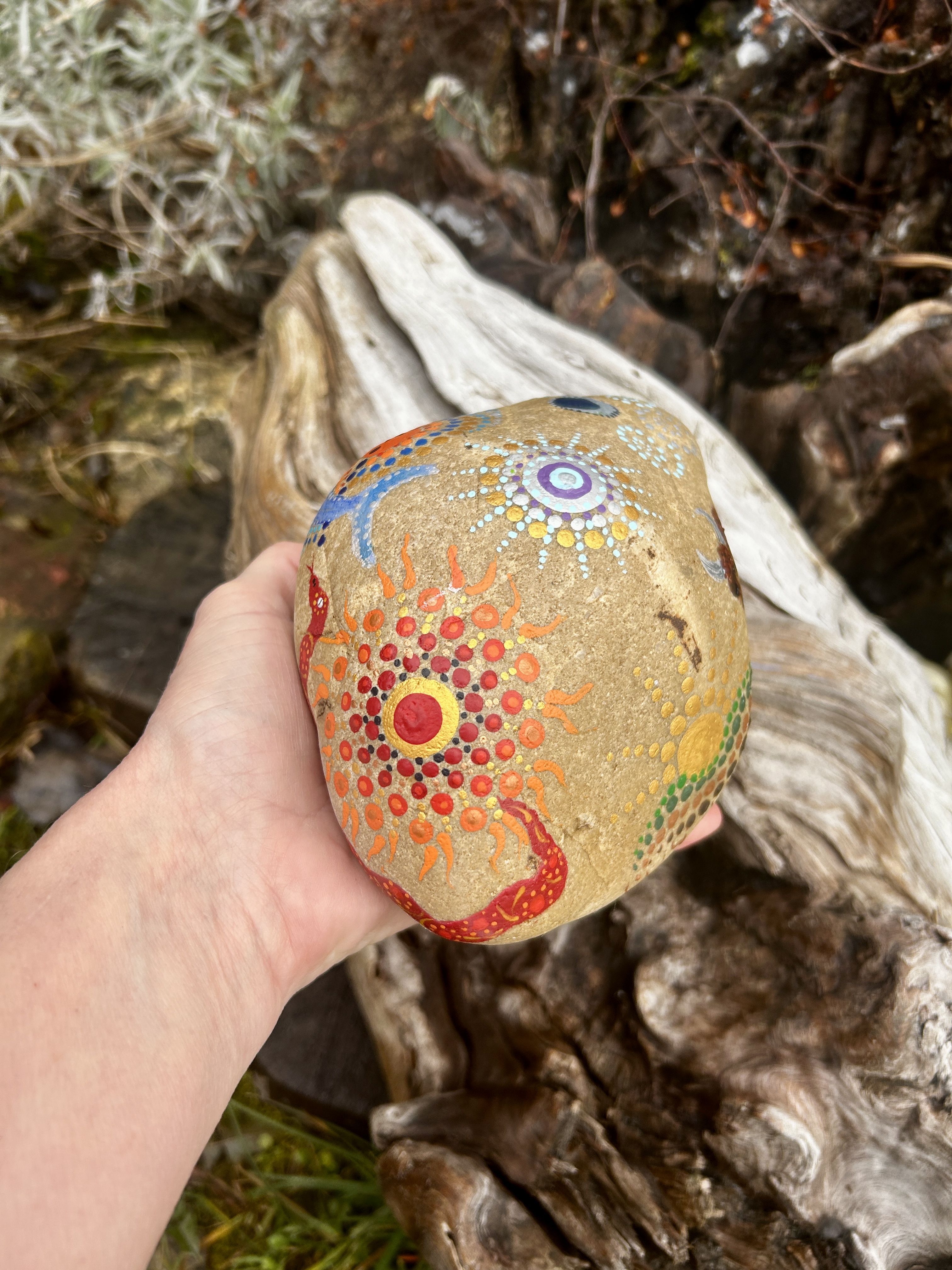 Stein in Dot Painting Technik bemalt mit Mandala in der Hand liegend