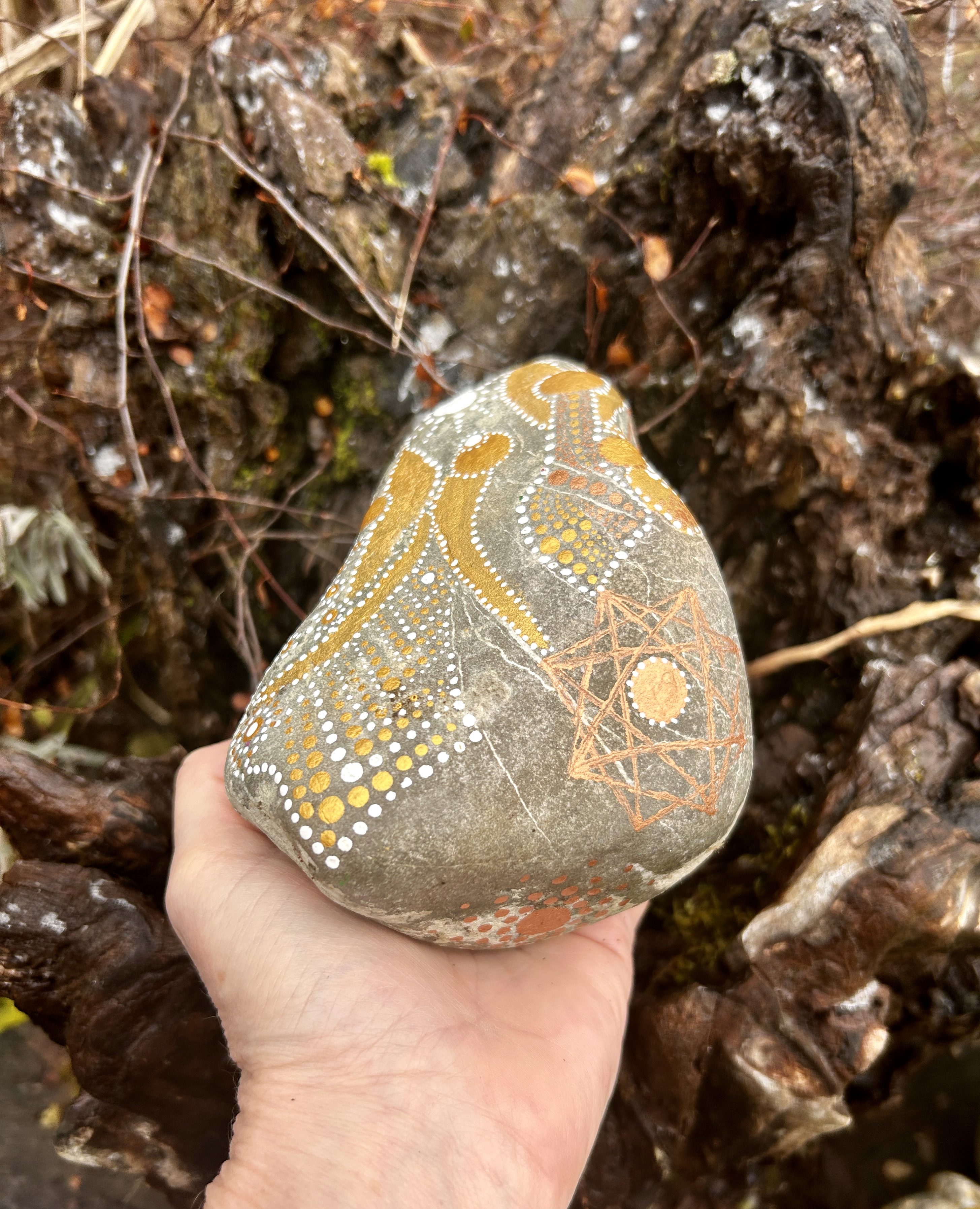 Stein mit einem Engel in Dot Painting Technik bemalt in Gold und weißin der Hand gehalten