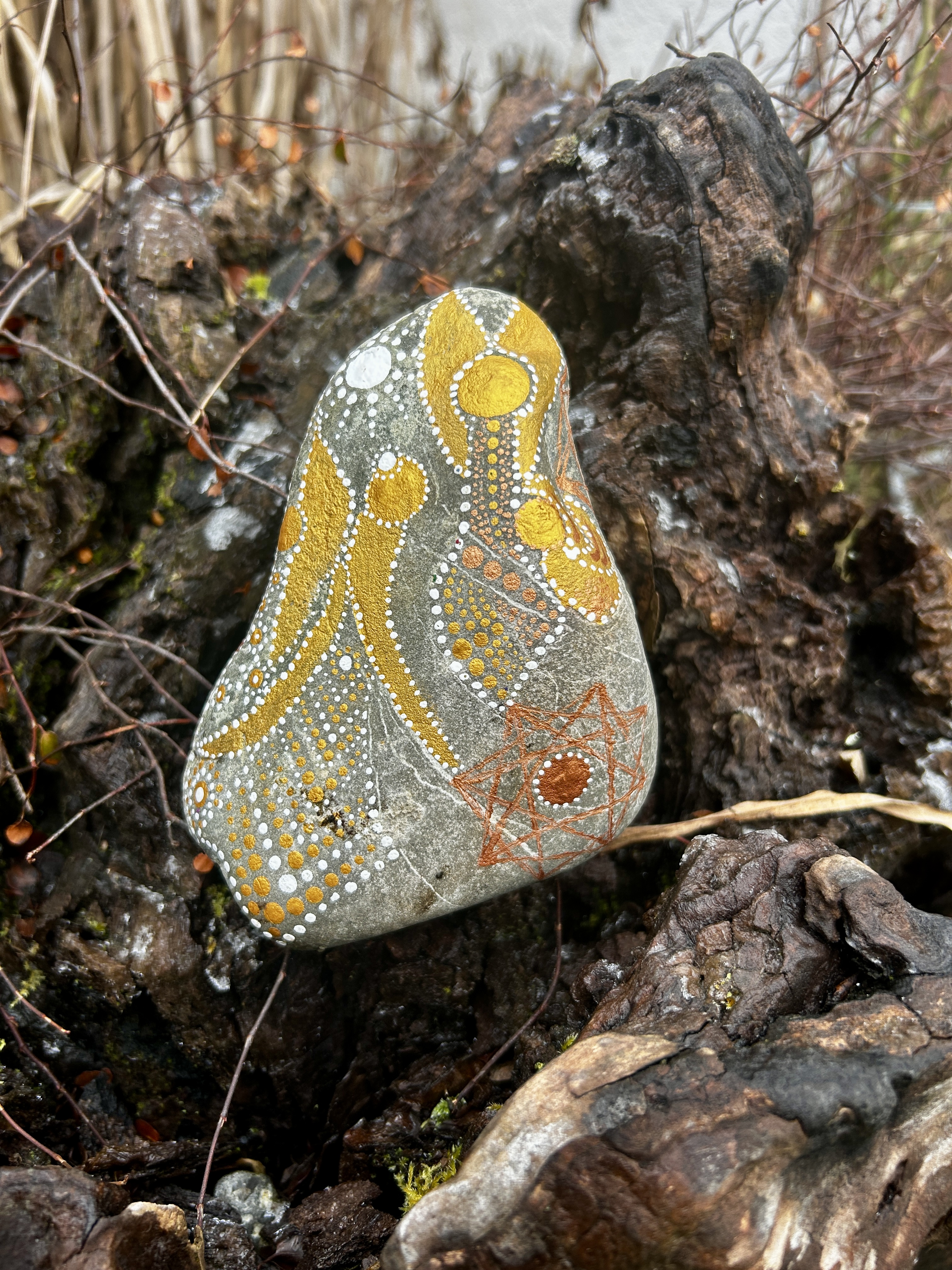 Stein mit mehreren Engelnl in Dot Painting Technik bemalt in Gold und weiß auf einer Wurzel stehend