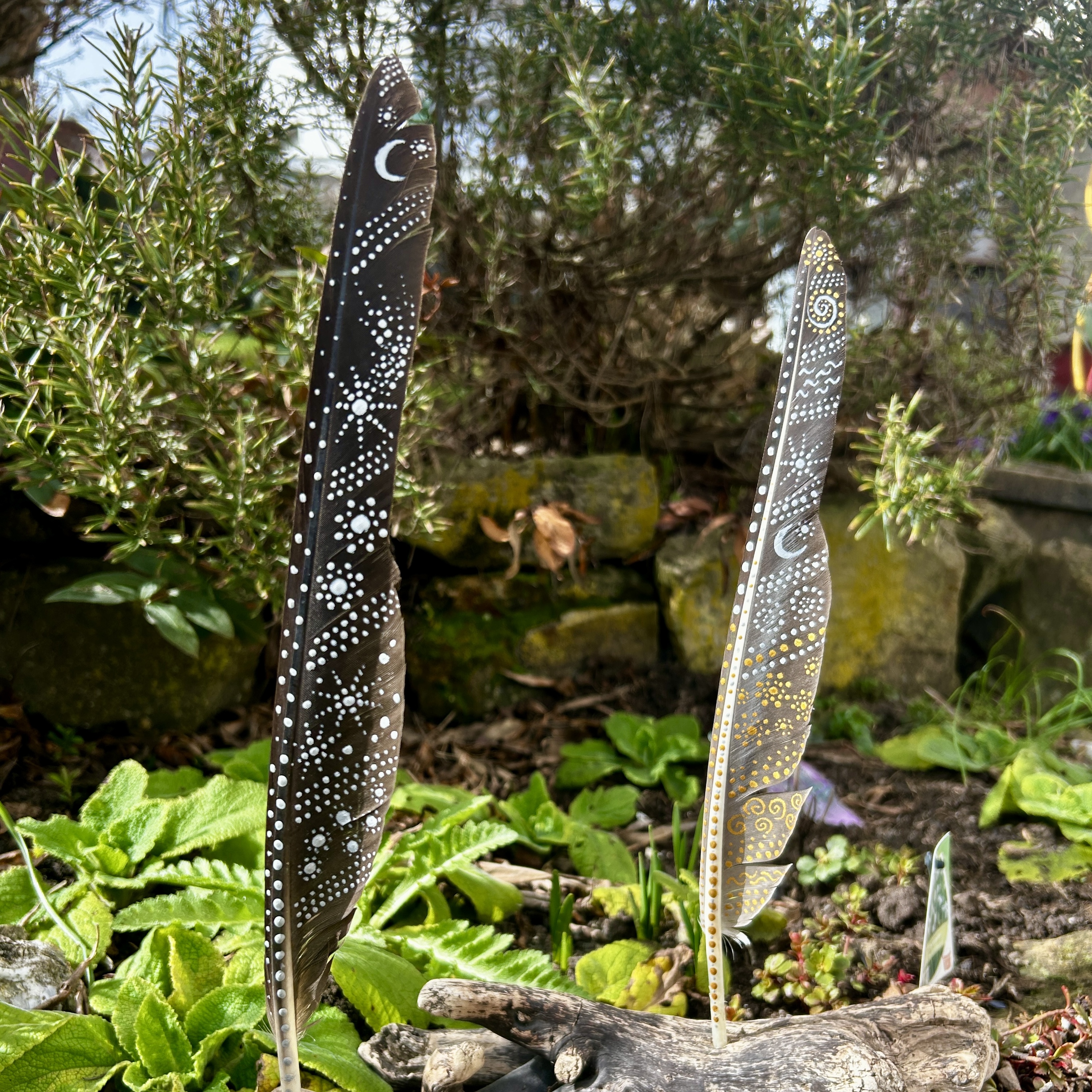 Zwei bemalte Federn im Garten stehend mit Gold- und Silber gestaltet