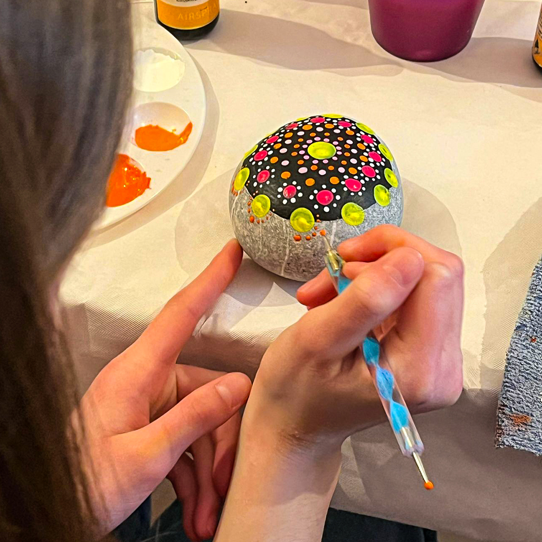 Workshopteilnehmerin beim Bemalen eines Mandalasteines
