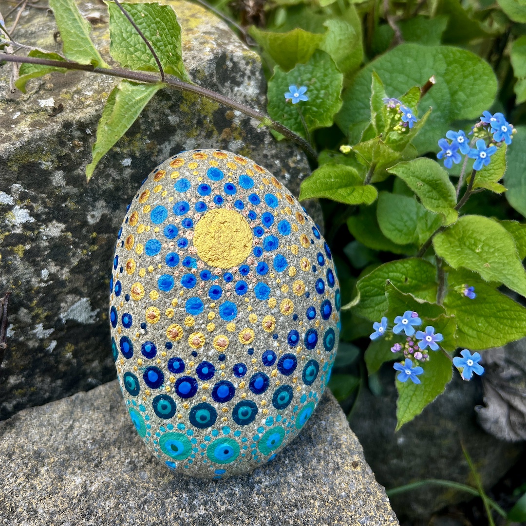 In Dot painting Technik bemalter Stein mit einem Mandala in Gold und Blautönen