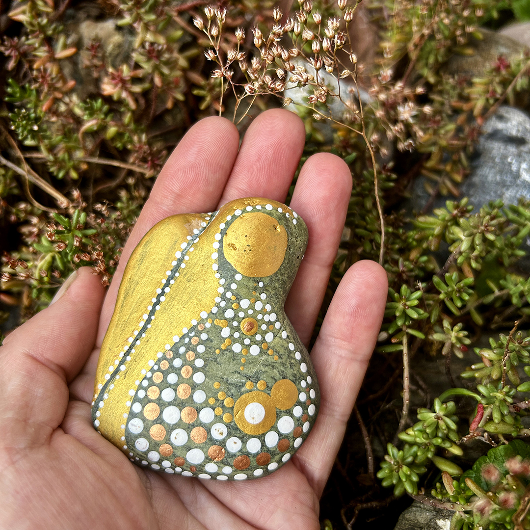 Ein Stein mit einem Engel bemalt in der Hand gehalten