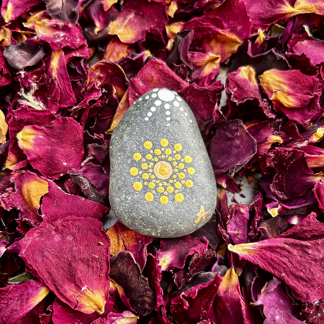 Bemalter Stein mit Mandala auf Rosenblätter