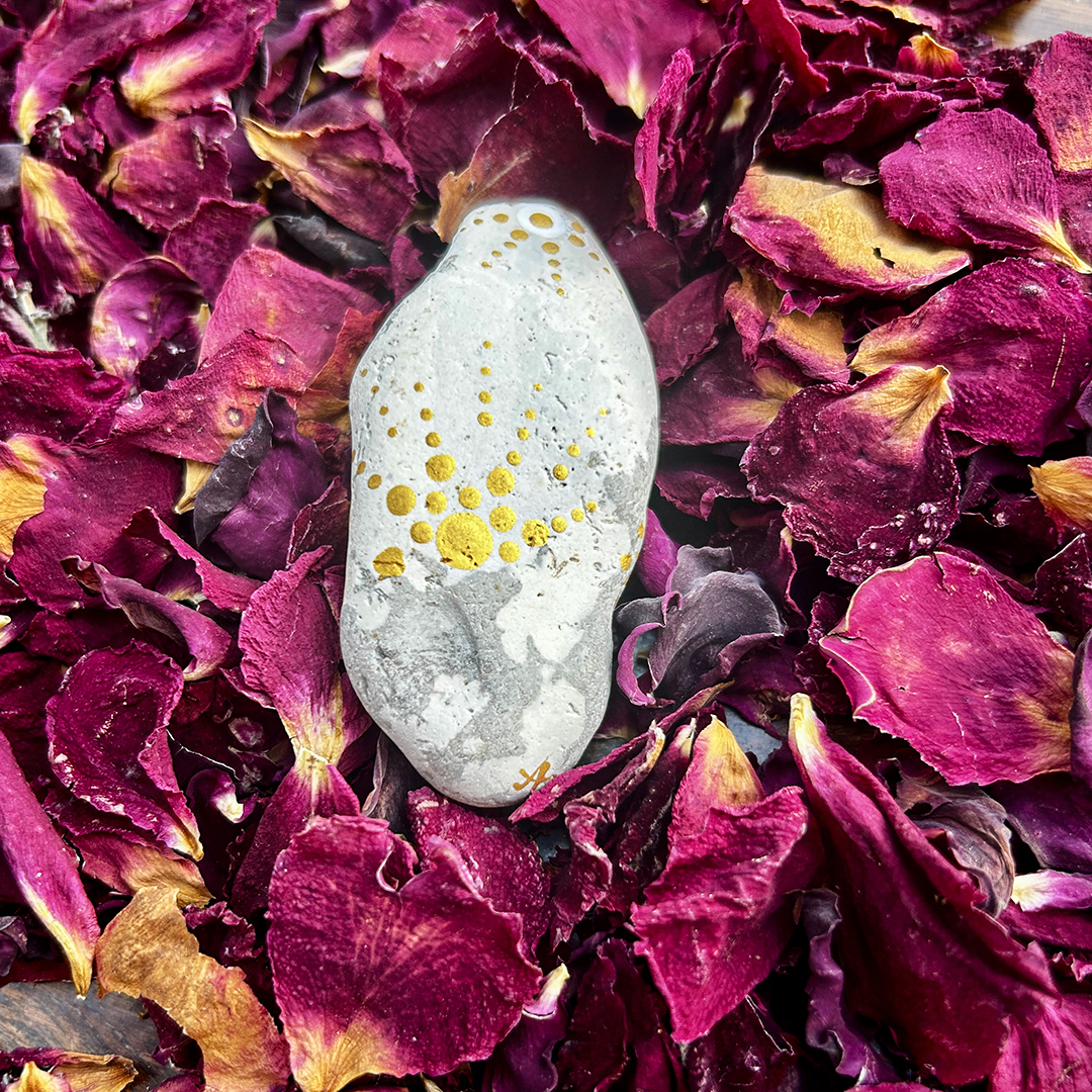 Bemalter Stein mit Stern auf Rosenblätter
