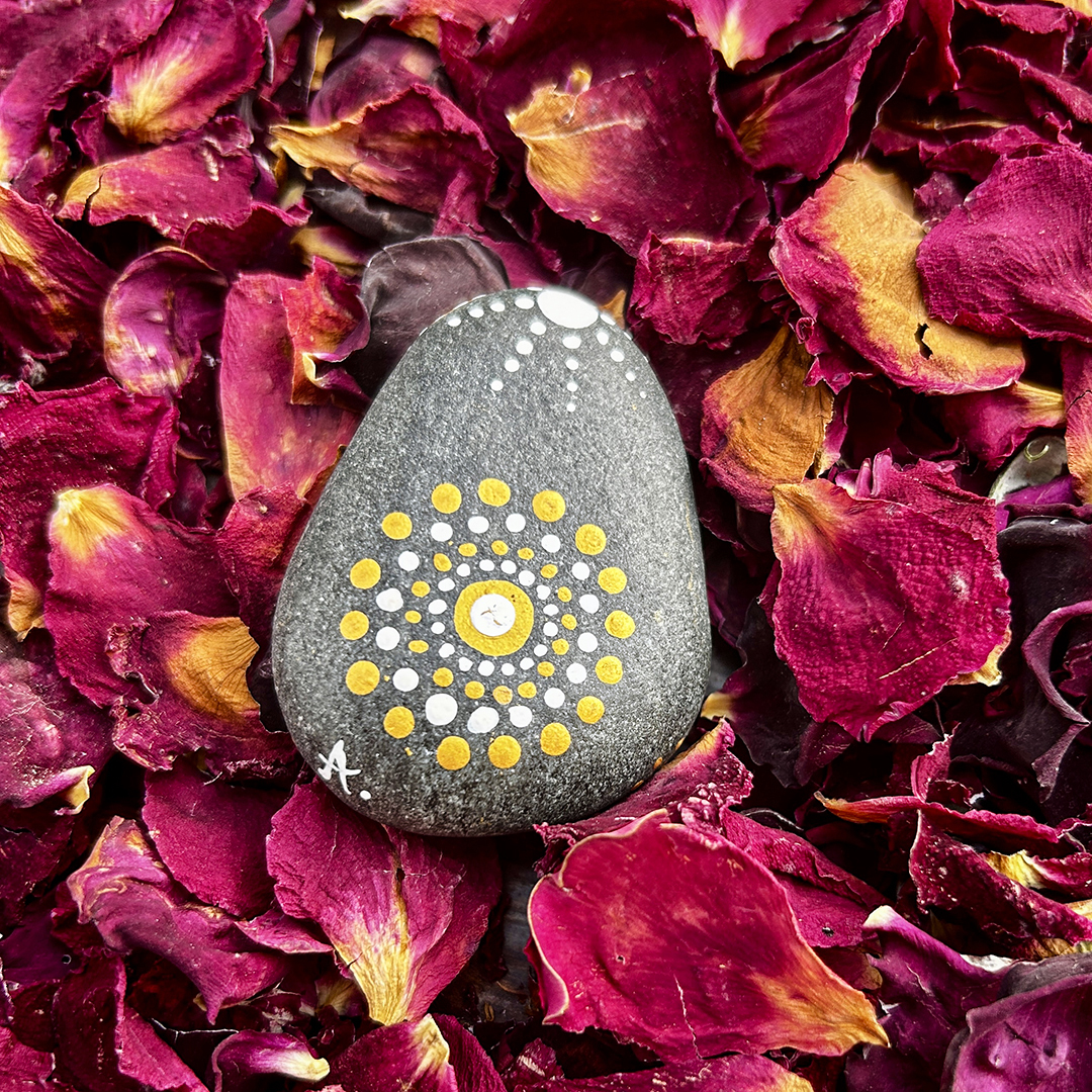 Bemalter Stein mit Mandala auf Rosenblätter