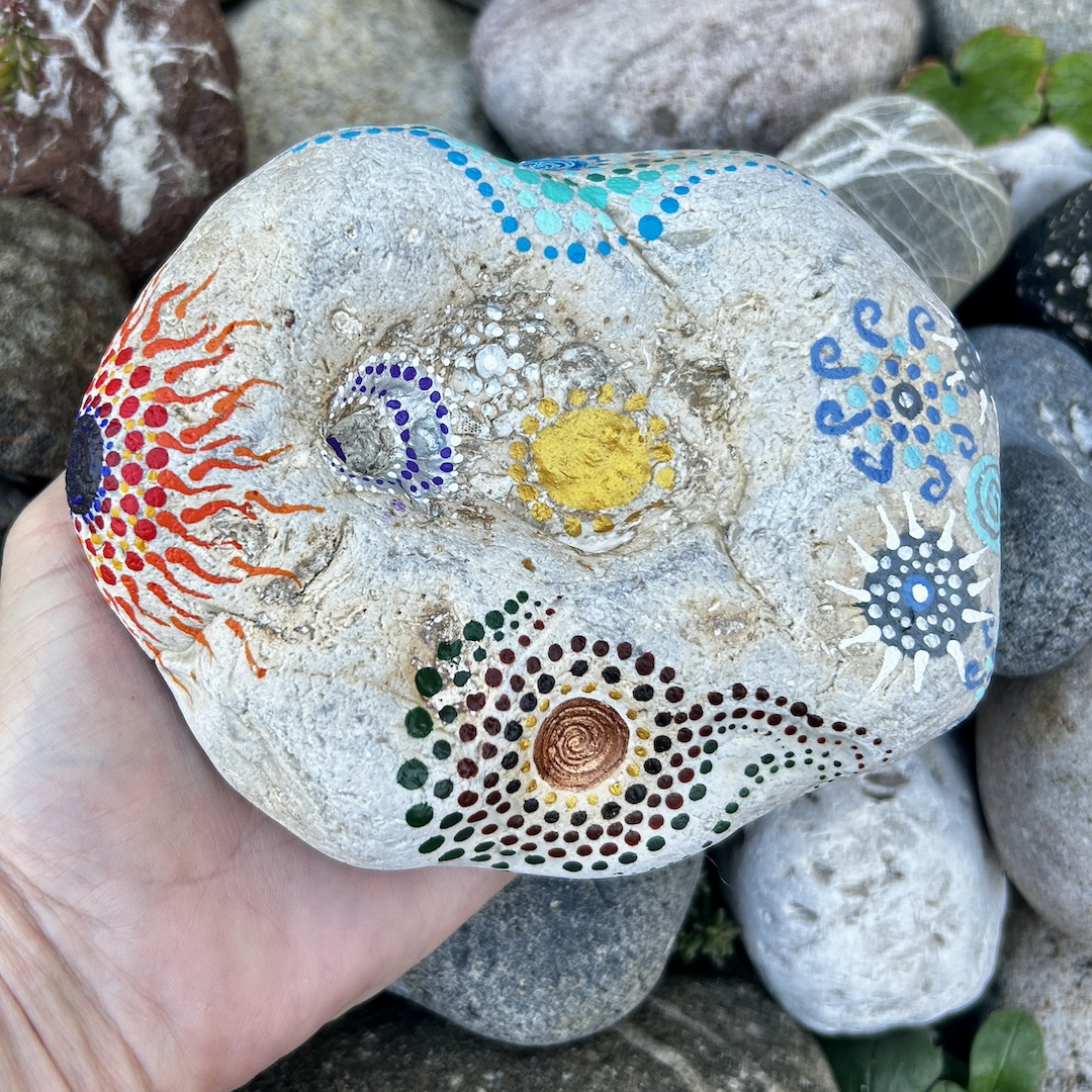 Heller Stein mit Mandalas gestaltet, der die vier Elemente zeigt in der Hand gehalten