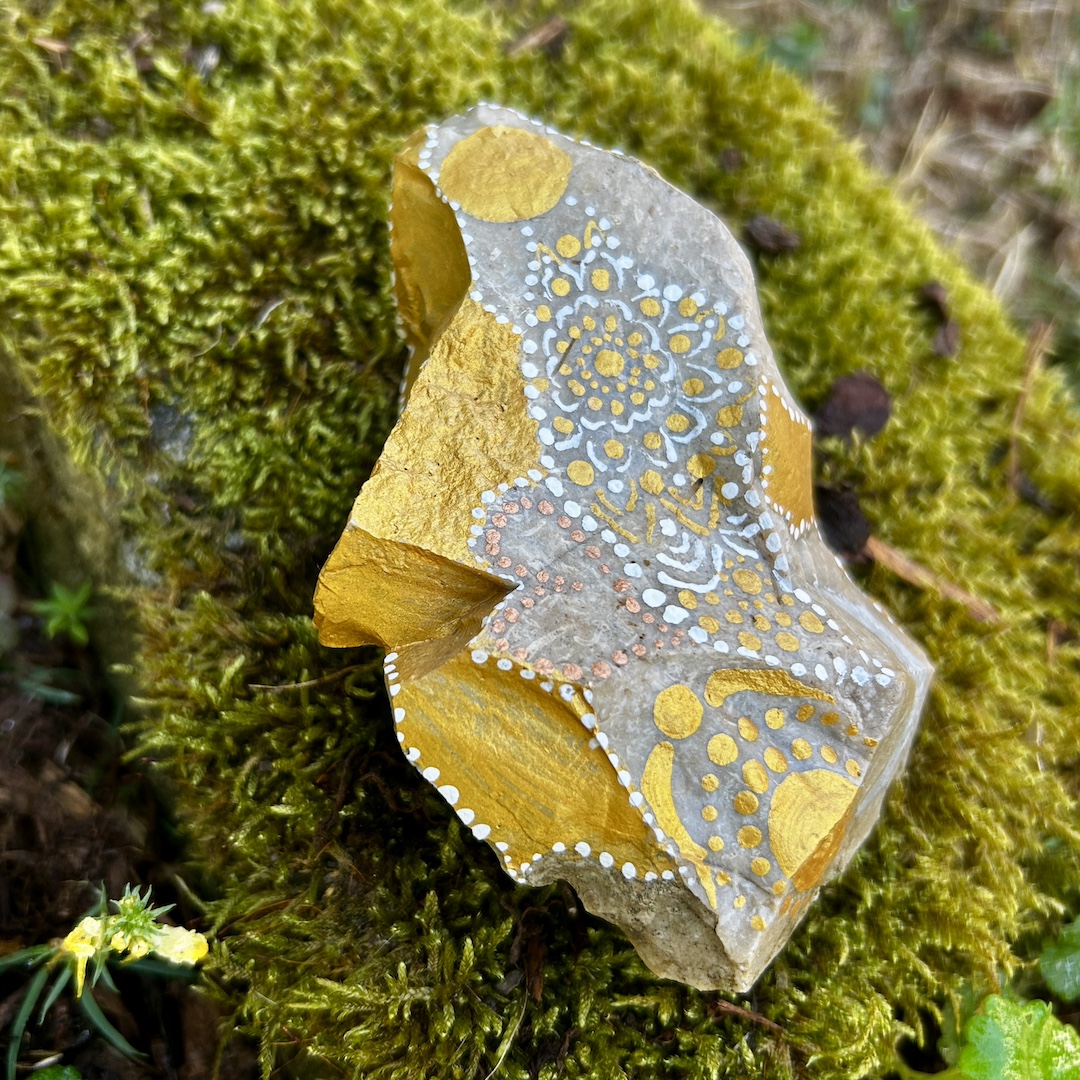 Stein mit einem Engel bemalt auf Moos liegend