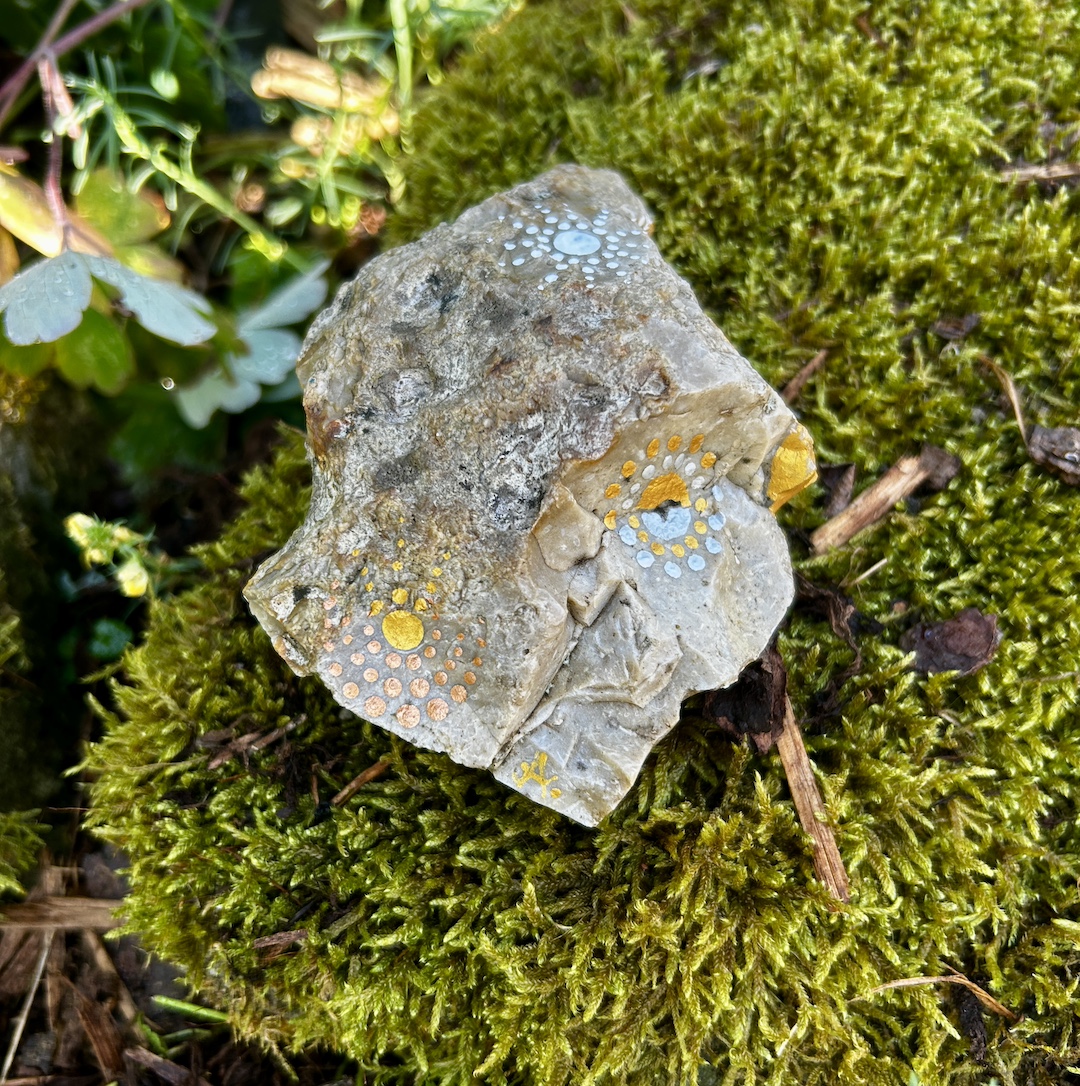 Stein mit einem Mandala bemalt auf Moos liegend