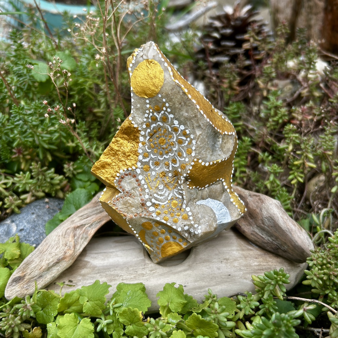 Stein mit einem Engel bemalt auf einem Holzständer im Garten stehend