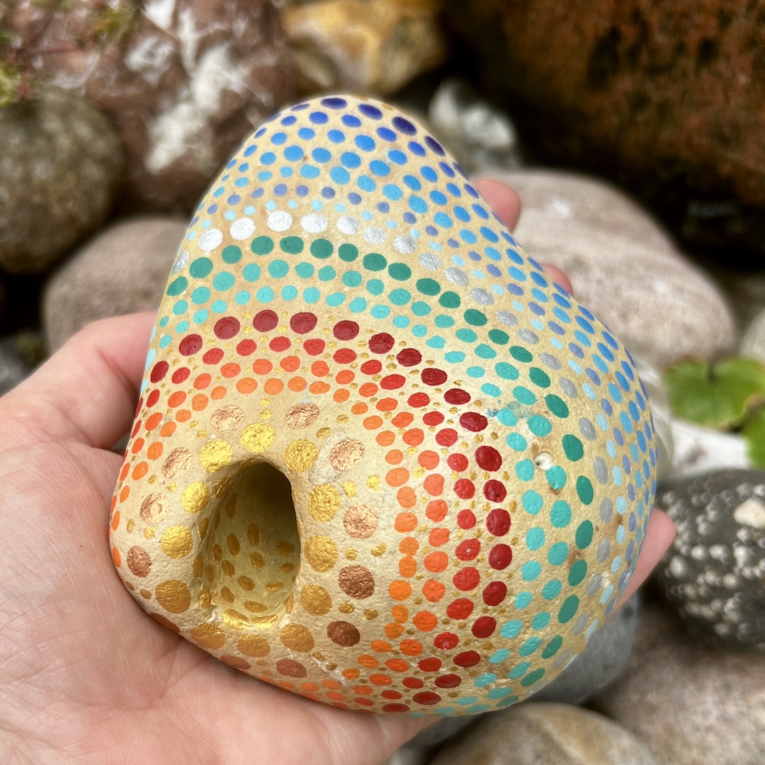 Stein in Gold- und Blautönen in Dot Painting Technik gestaltet in der Hand gehalten