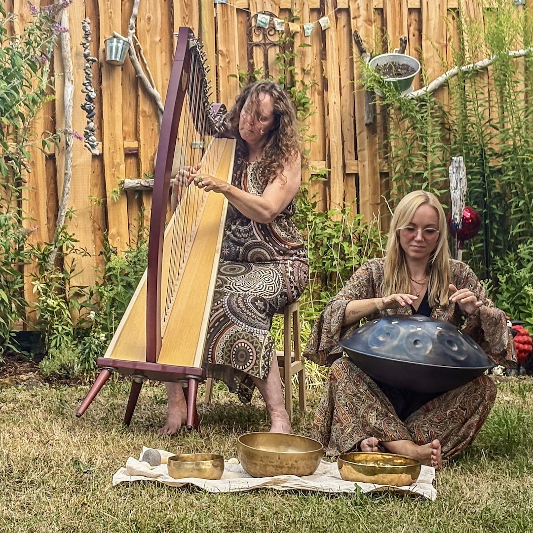 Lucie spielt Handpan und Anja spielt Harfe im Garten