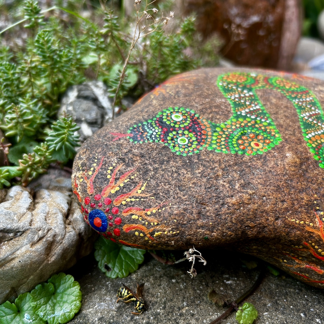 Ein rötlicher Stein mit Schlange in Grüntönen im Detail der Kopf