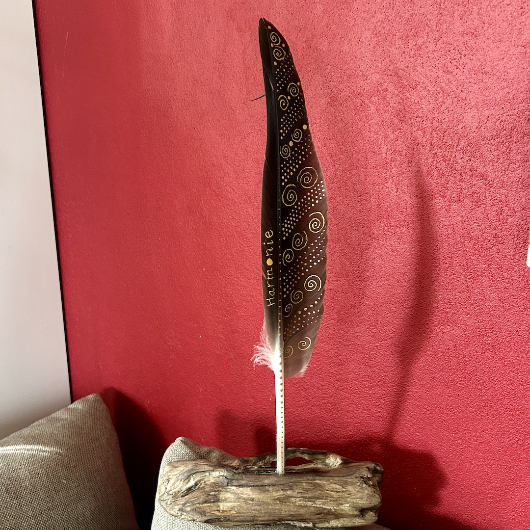 In Gold bemalte Feder vor roter Wand