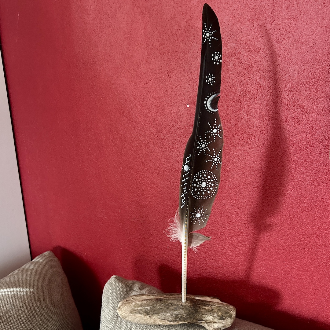 In Silber mit Mond und Sterne bemalte Feder vor roter Wand