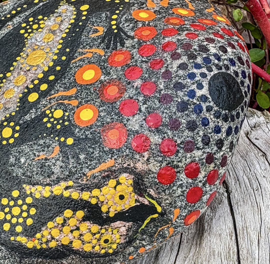 Stein mit einem Feuersalamder in Dot Painting Technik gestaltet auf Holz liegend