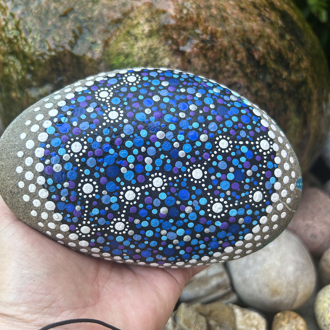 Bemalter Stein mit Sternbild Fische in der Hand