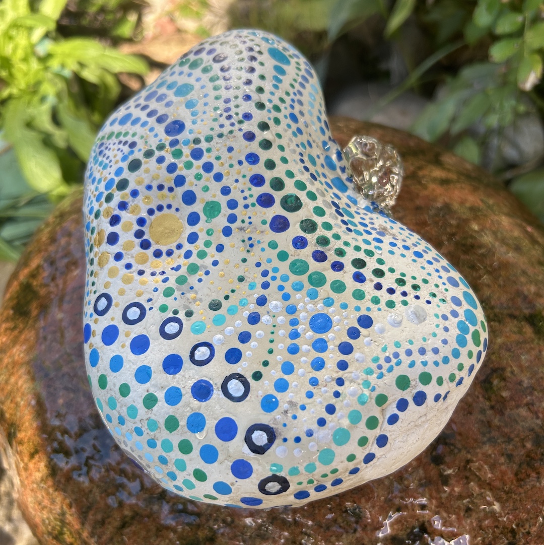 Stein im Garten liegend in Blau- und Grüntönen bemalt