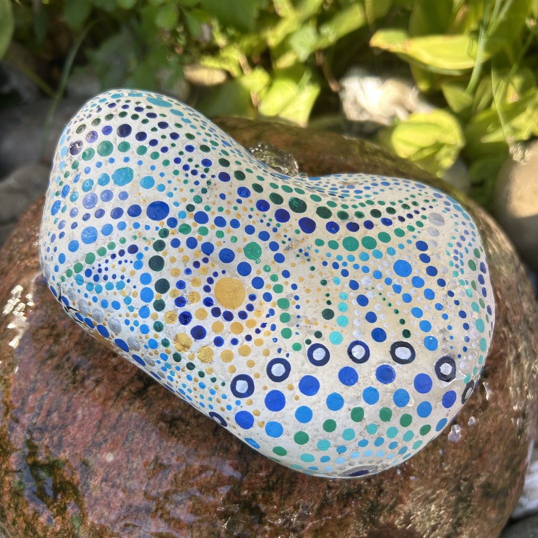 Stein im Garten liegend mit Blau- und Grüntönen bemalt