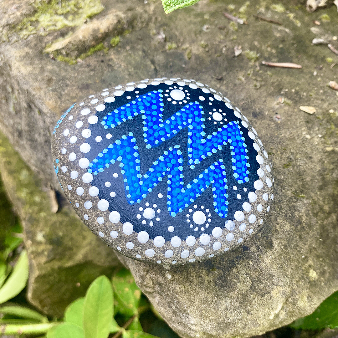 Bemalter Stein mit astrologischen Symbol Wassermann auf Stein liegend