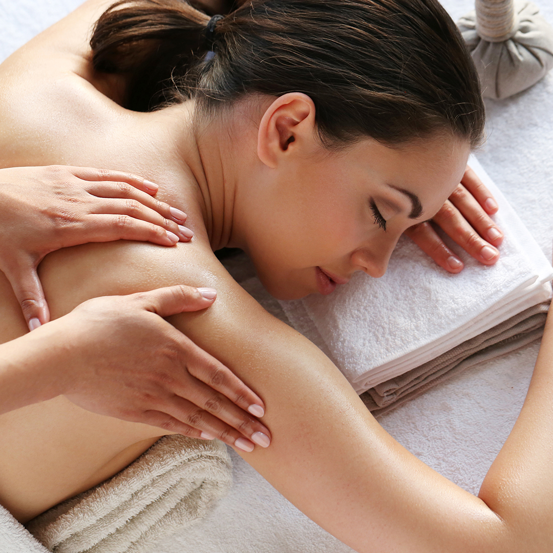 Frau auf Massageliege liegend wird massiert