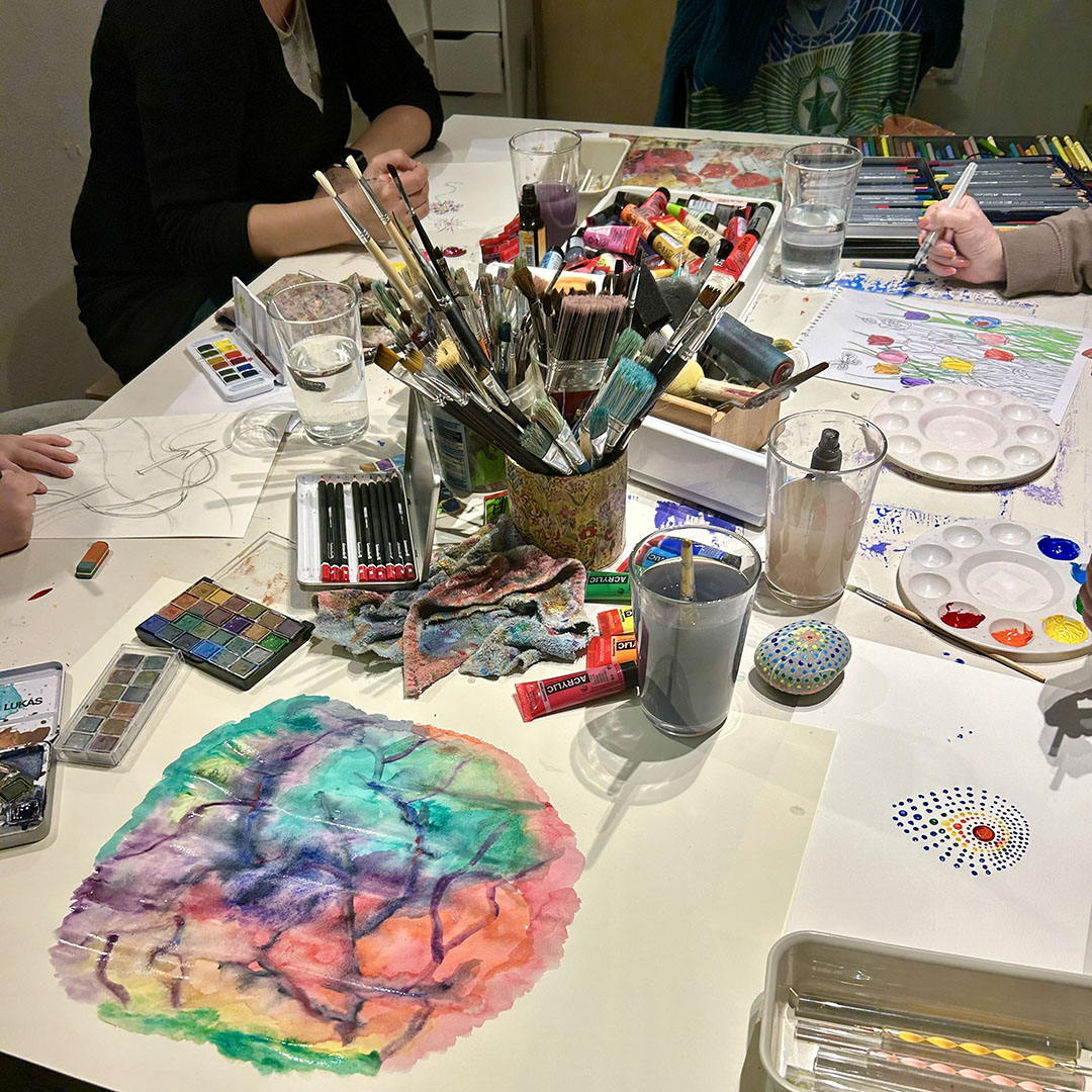 Farben, Pinsel und ein Bild auf dem Tisch