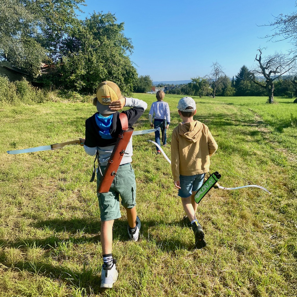 Kinder mit Bögen und Pfeileköcher auf Wiese