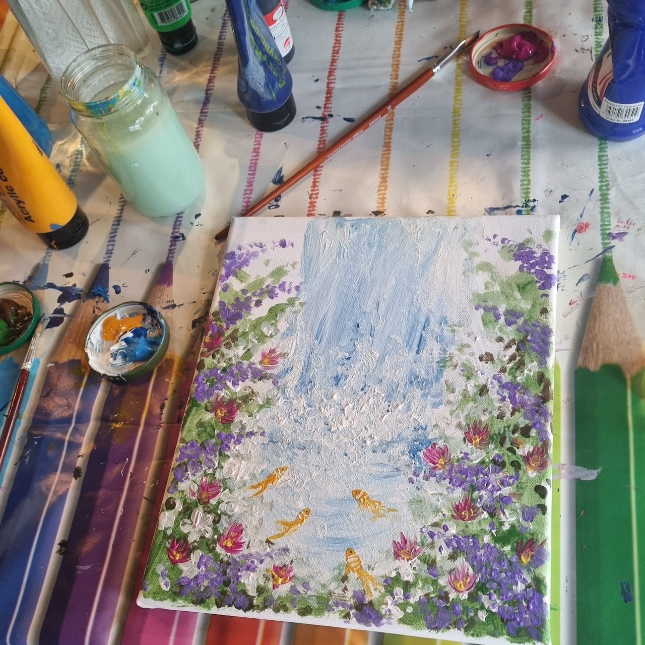 Farben, Stifte und Leinwand mit gemalten Blumen